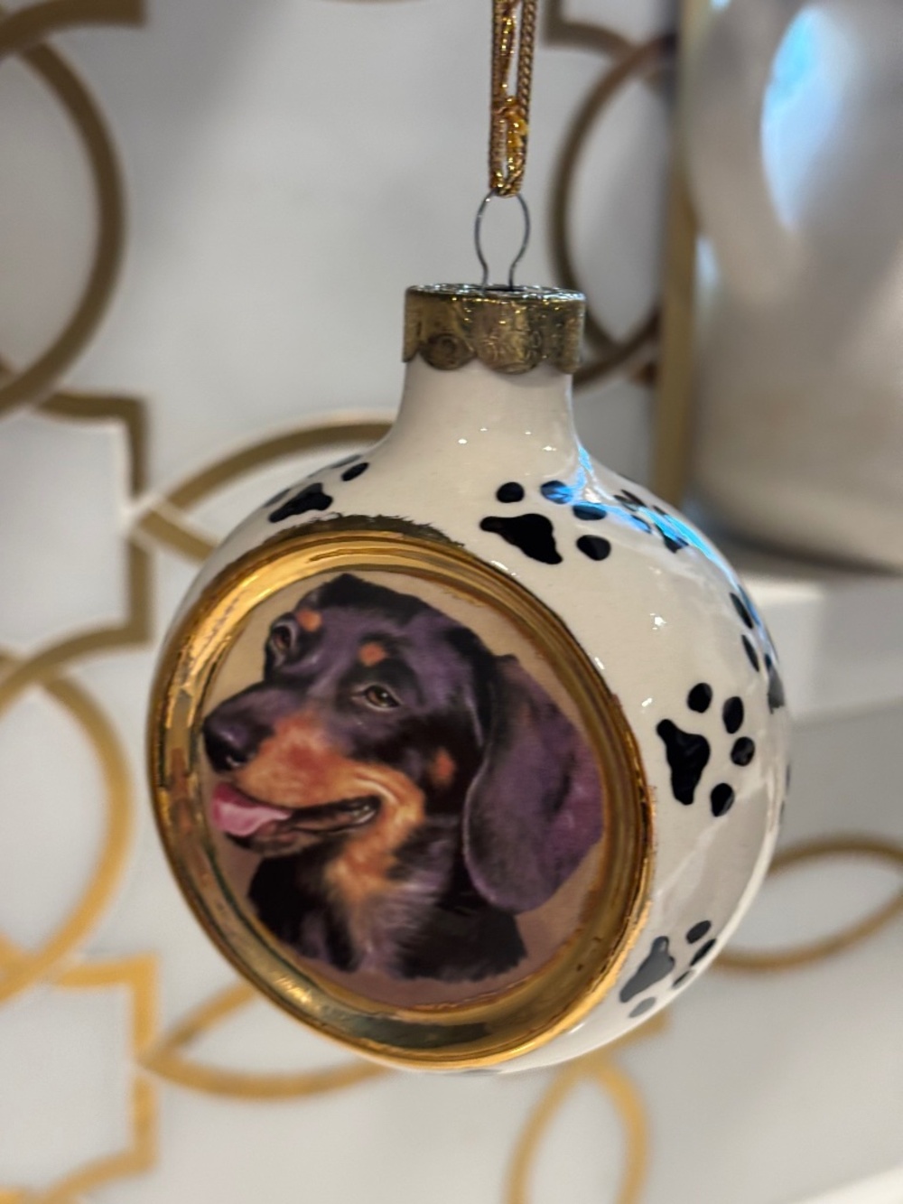 Dachshund Christmas ball ornament featuring glossy white finish with black paw